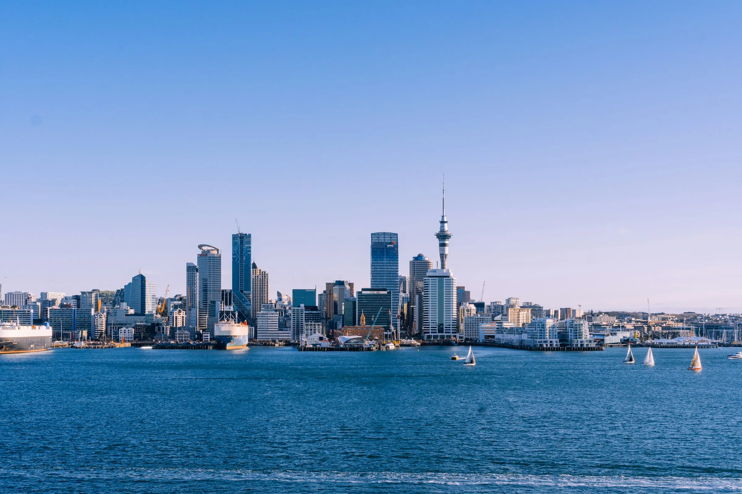Auckland's city skyline and Sky Tower across the Waitematā Harbour on a clear, sunny day