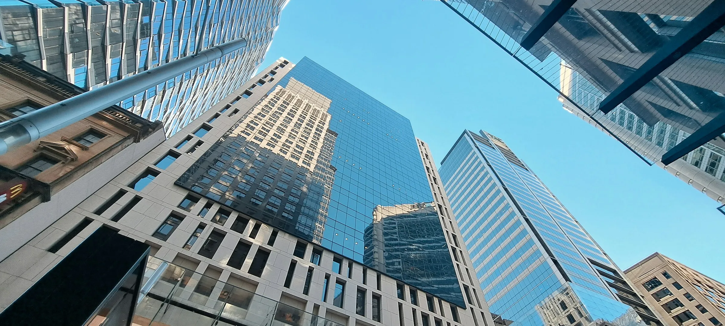 Glass office towers seen from street level against a clear blue sky